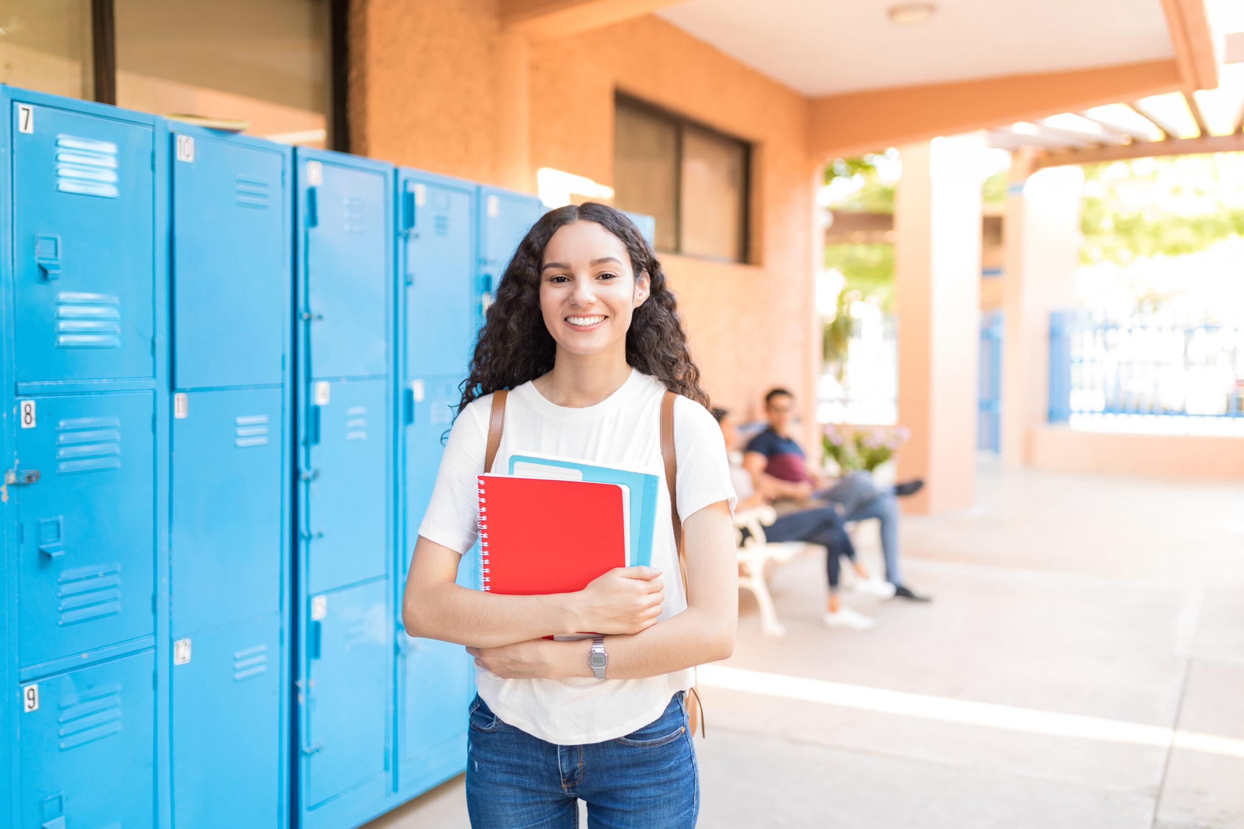 Caucasian student with books standing near locker in college hallway