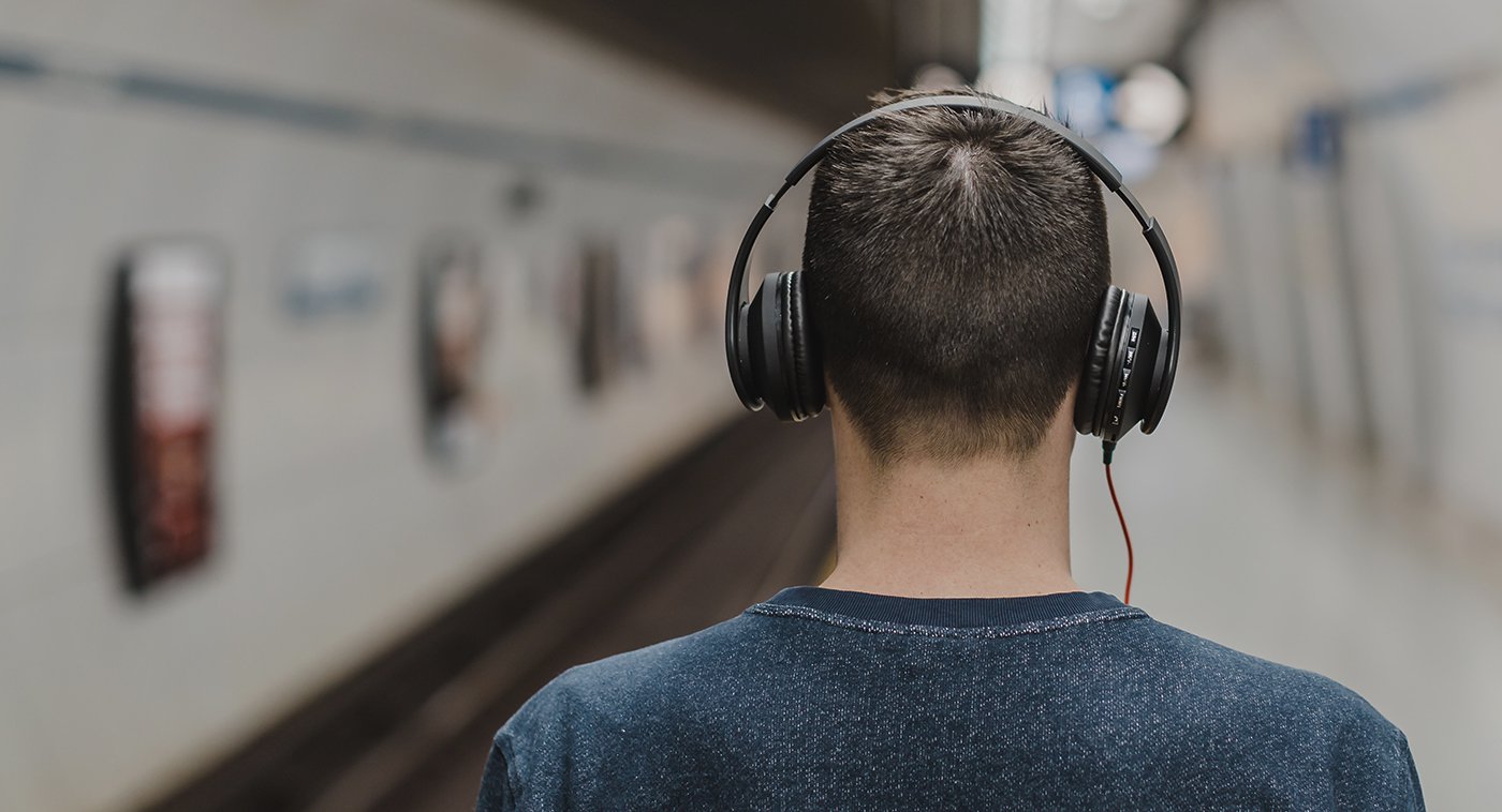 Young man waiting for subway with large headphones